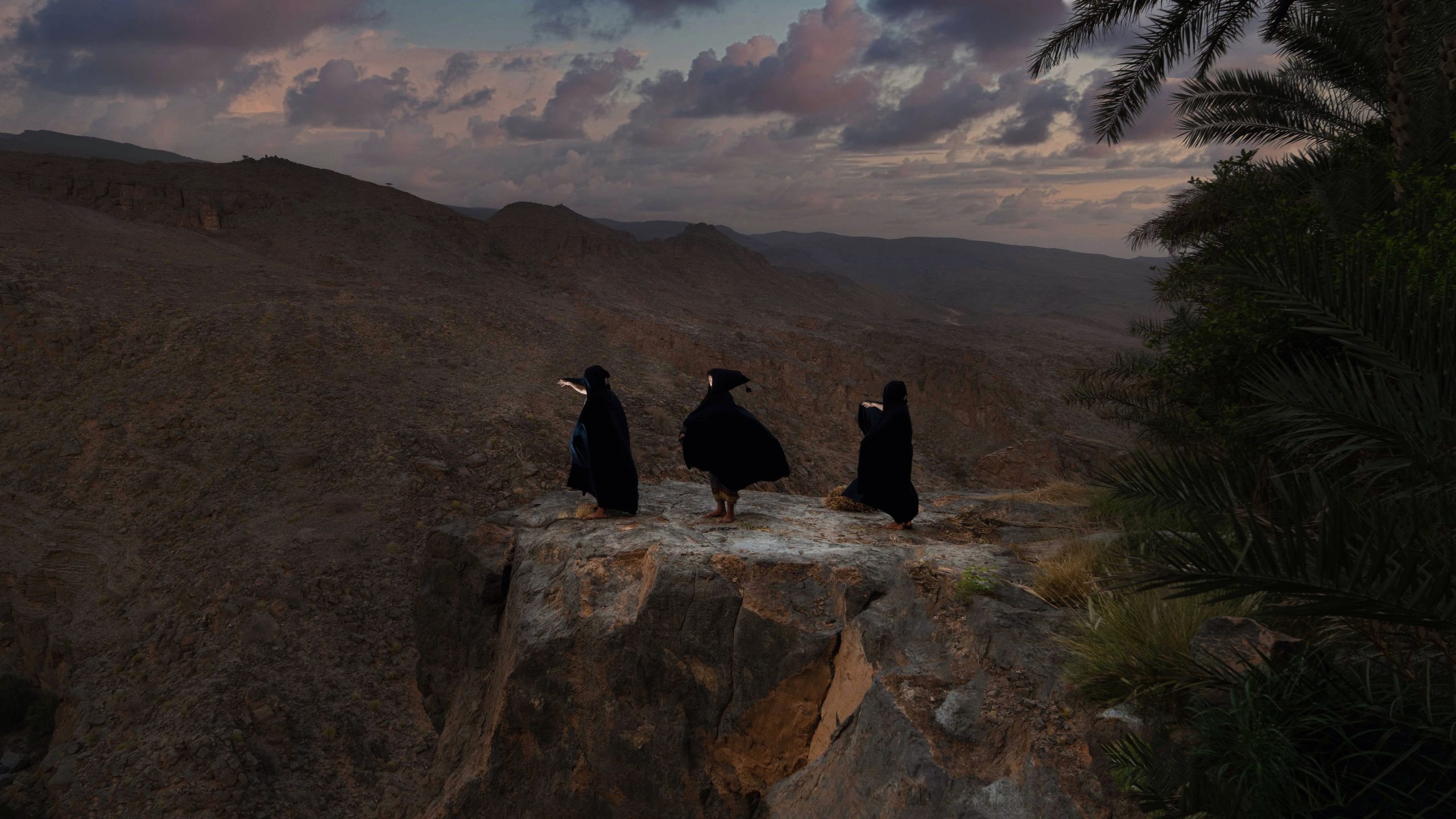 Truth: three black-robed figures overlooking a mountainous Omani landscape — Omani photographer AMRALI, AA Editions